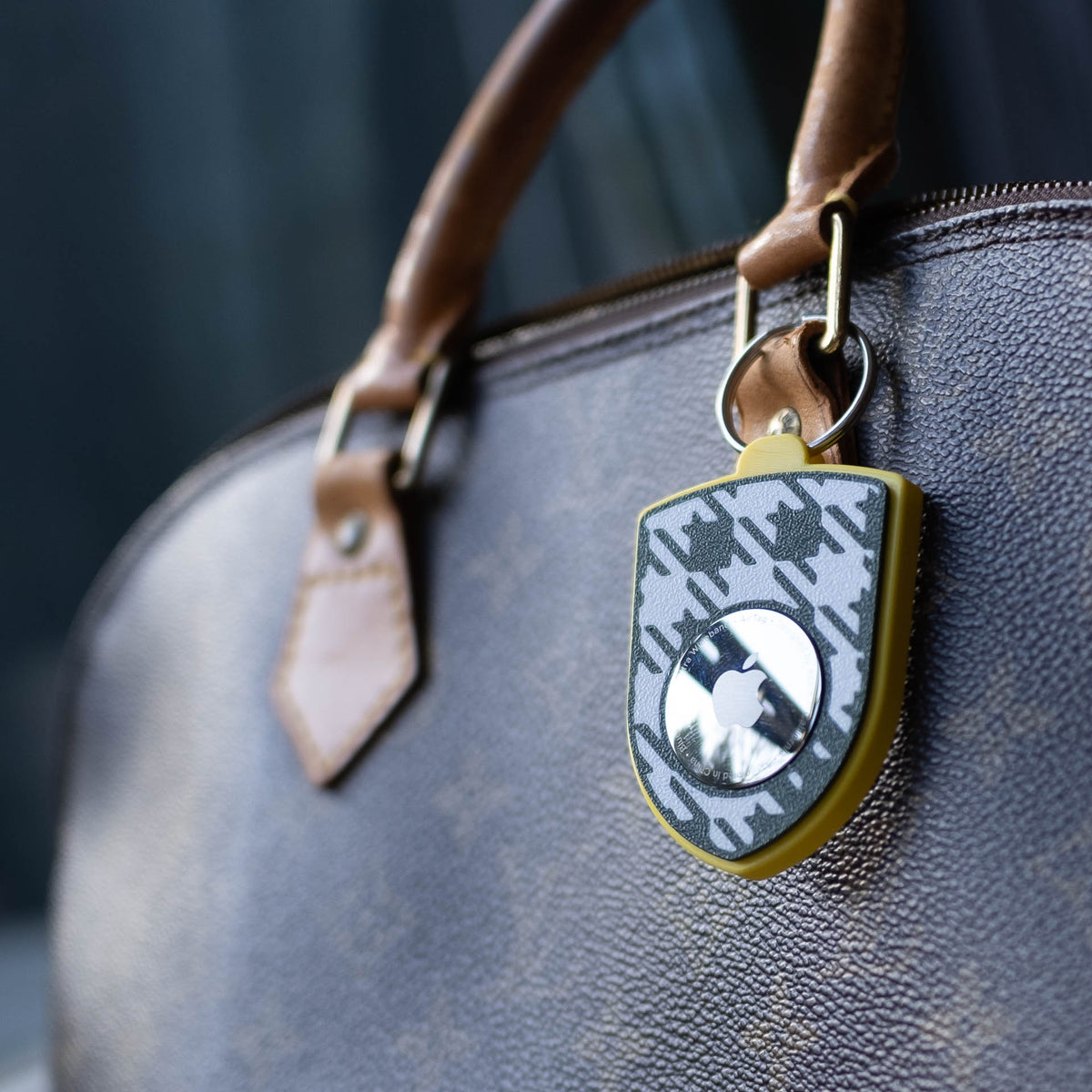 Gelb-grüner AirTag-Schlüsselanhänger mit Pepita an einer Handtasche