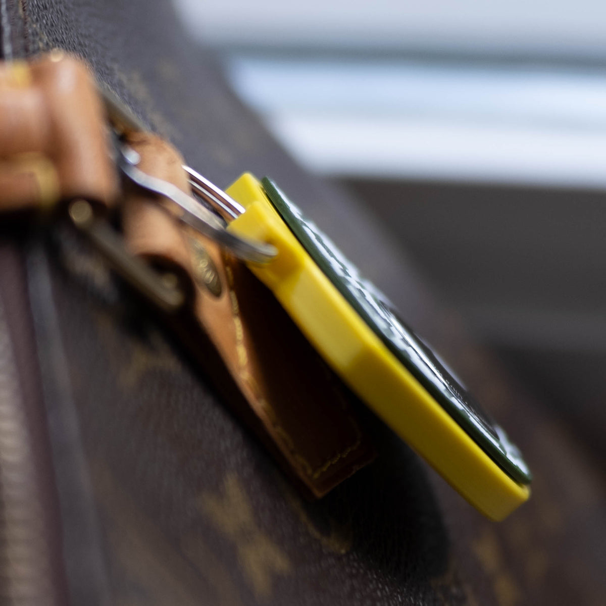 Seitenansicht des gelb-grünen AirTag-Schlüsselanhängers an einer Handtasche