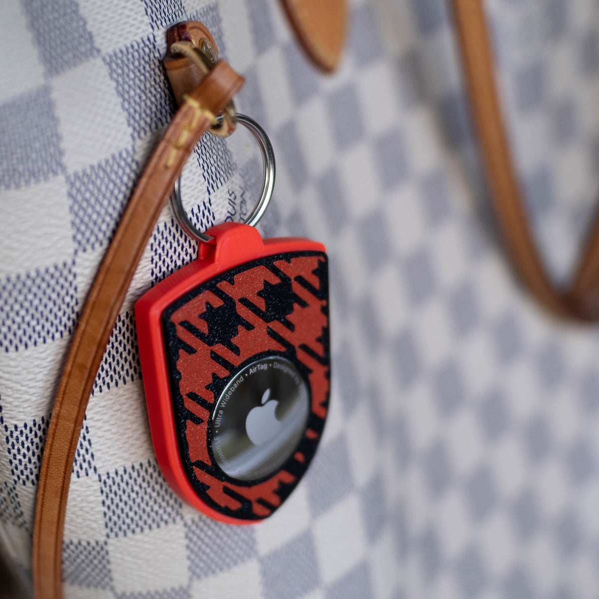 Rot-schwarzer AirTag-Schlüsselanhänger mit Pepita an einer Handtasche