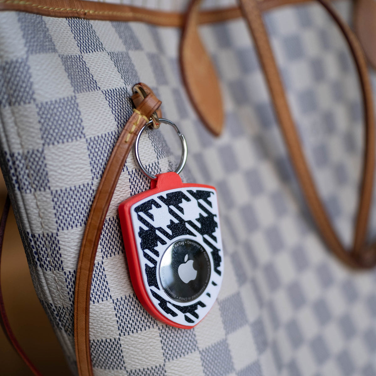 Rot-schwarzer AirTag-Schlüsselanhänger mit Pepita an einer Handtasche