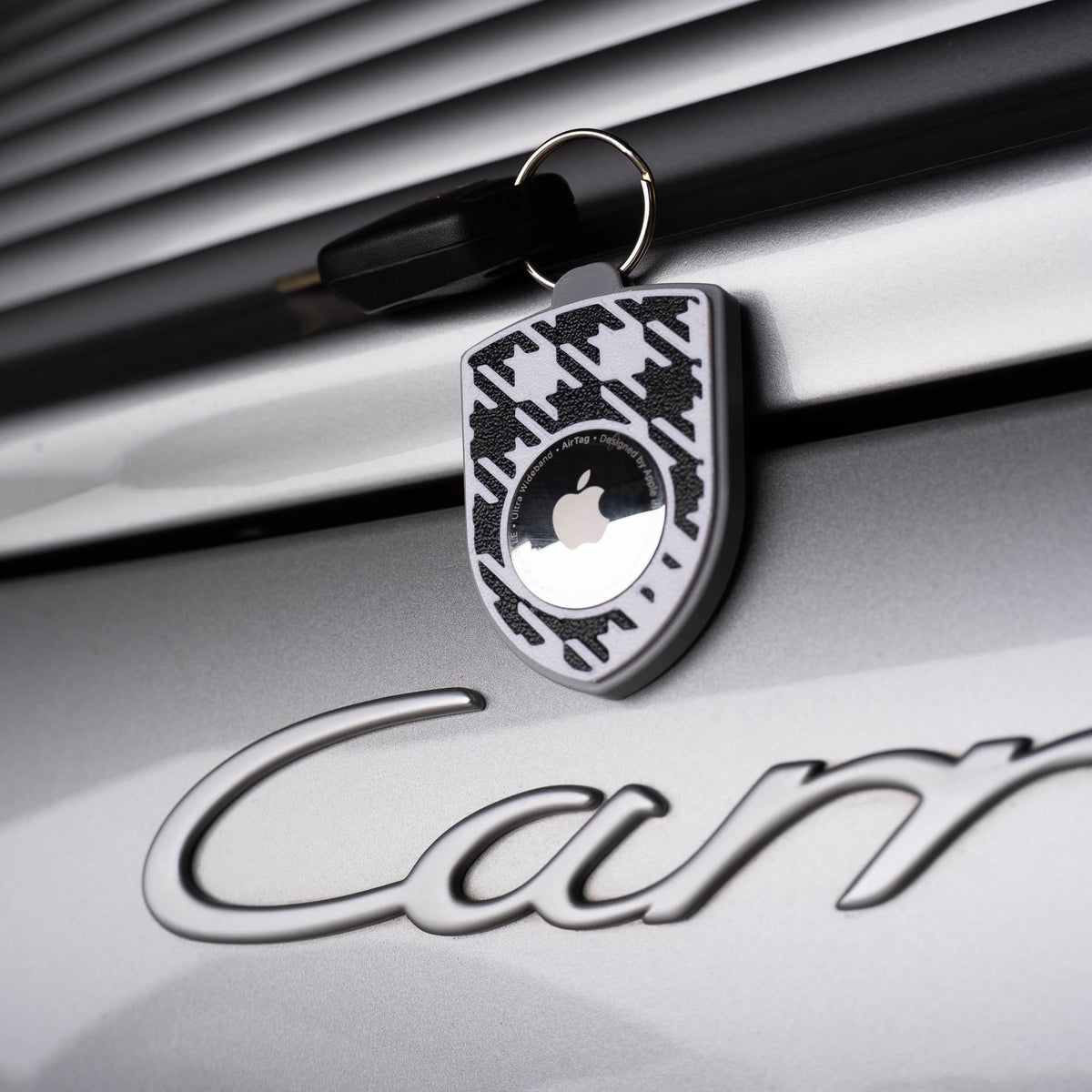 Grau-schwarzer AirTag-Schlüsselanhänger mit Pepita am Porsche Carrera
