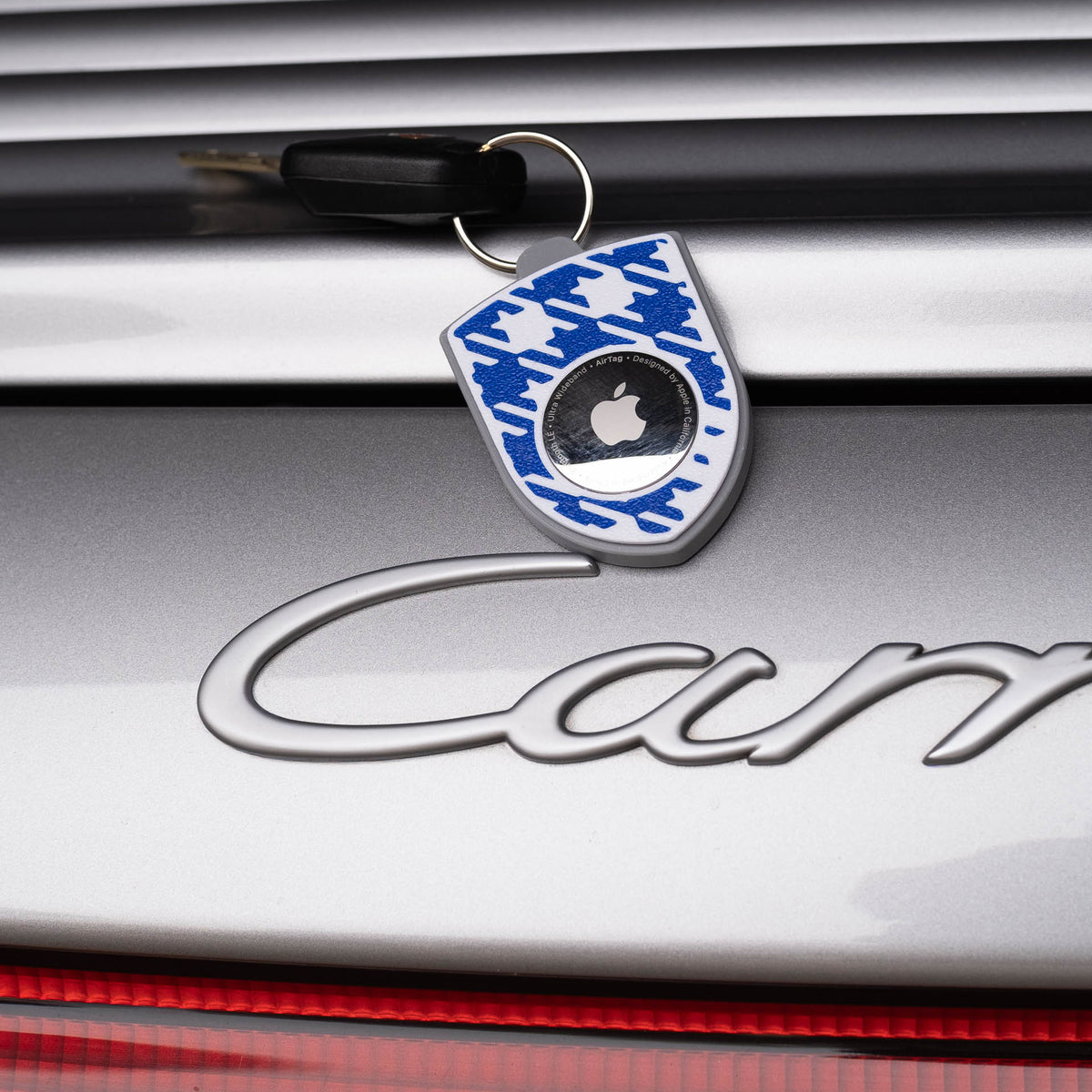 Grau-blauer AirTag-Schlüsselanhänger mit Pepita am Porsche Carrera
