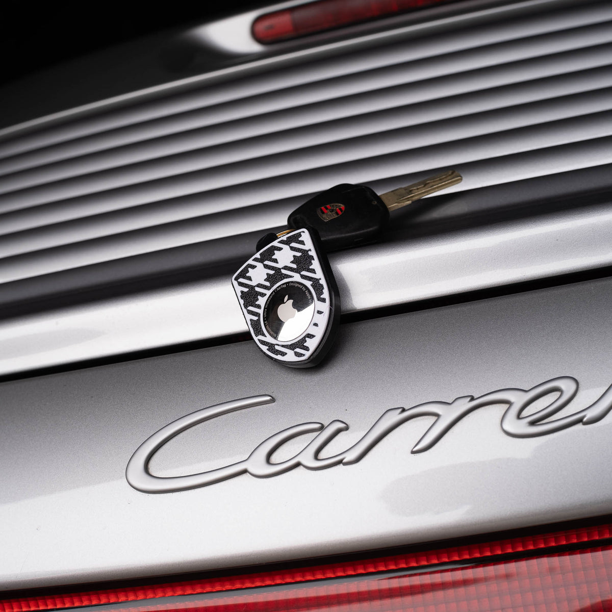 Grau-schwarzer AirTag-Schlüsselanhänger mit Pepita am Porsche Carrera