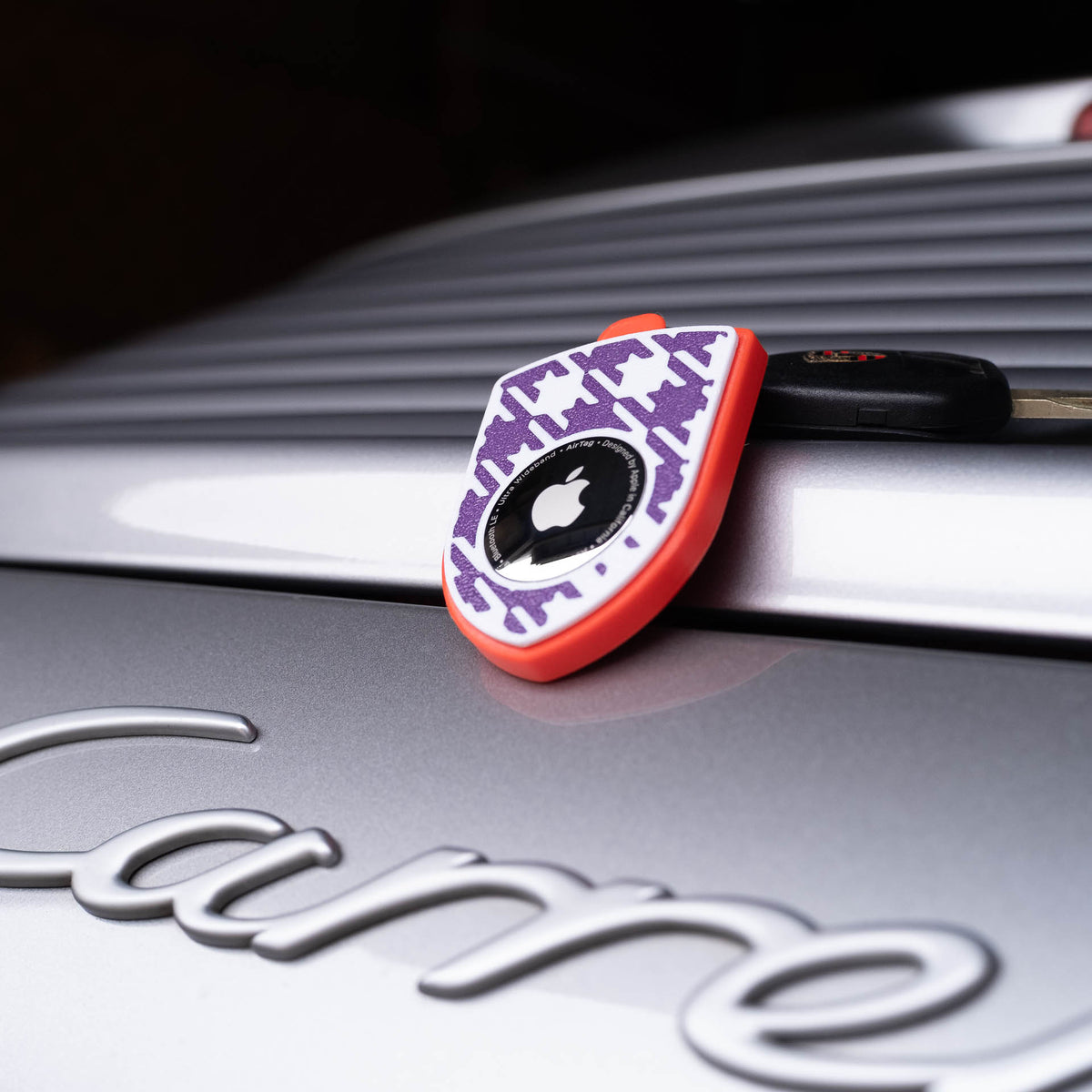 Rot-violetter AirTag-Schlüsselanhänger mit Pepita am Porsche Carrera
